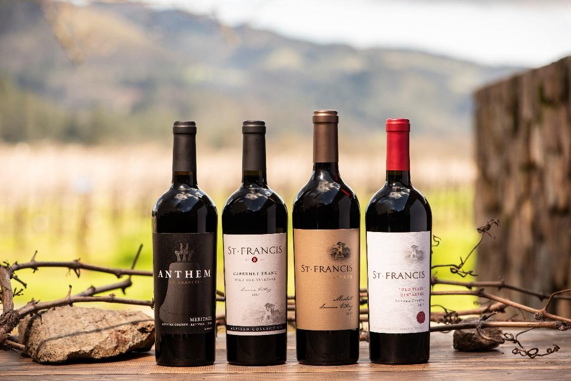 Four bottles from the St. Francis Winery portfolio, standing among vineyard rocks and branches.